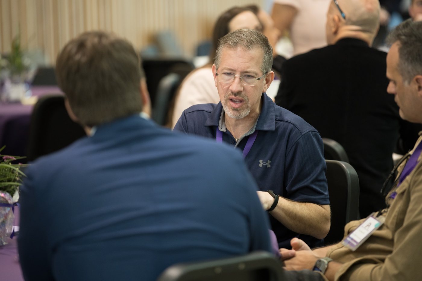 Two people in a focused business conversation across a table at a Founders Arena session.