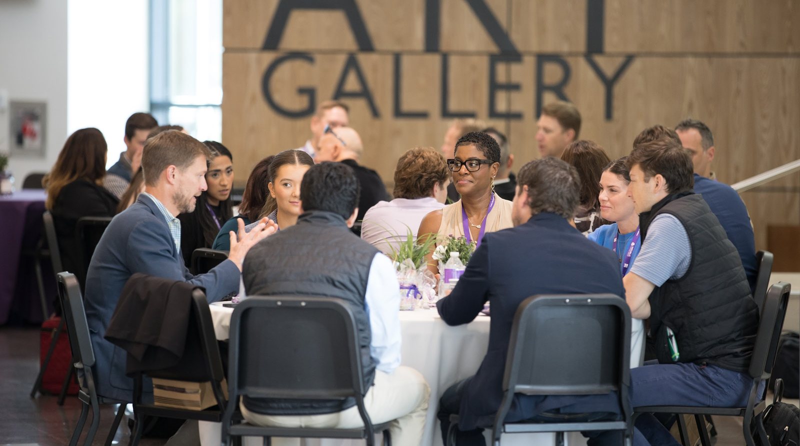 Founders, operators and investors in conversation around tables at a Founders Arena convening, with the venue's ART Gallery lettering on the wall behind them.